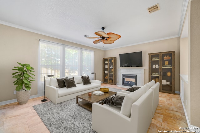 living room with a textured ceiling, ceiling fan, ornamental molding, and light tile patterned flooring