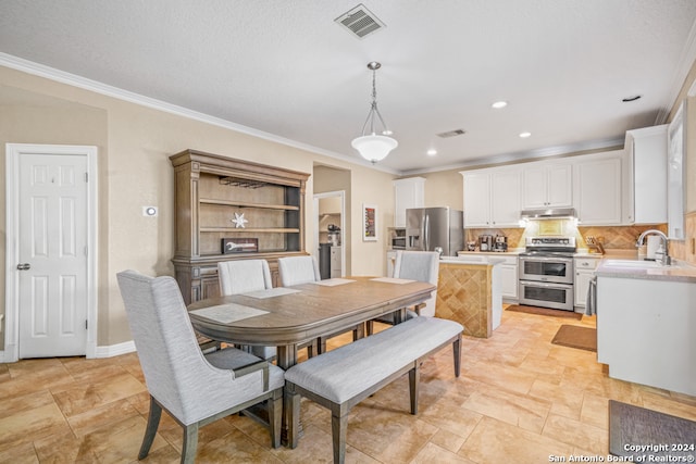 dining space featuring sink, a textured ceiling, and ornamental molding