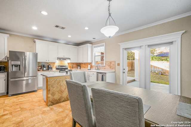 interior space featuring backsplash, white cabinets, decorative light fixtures, and appliances with stainless steel finishes