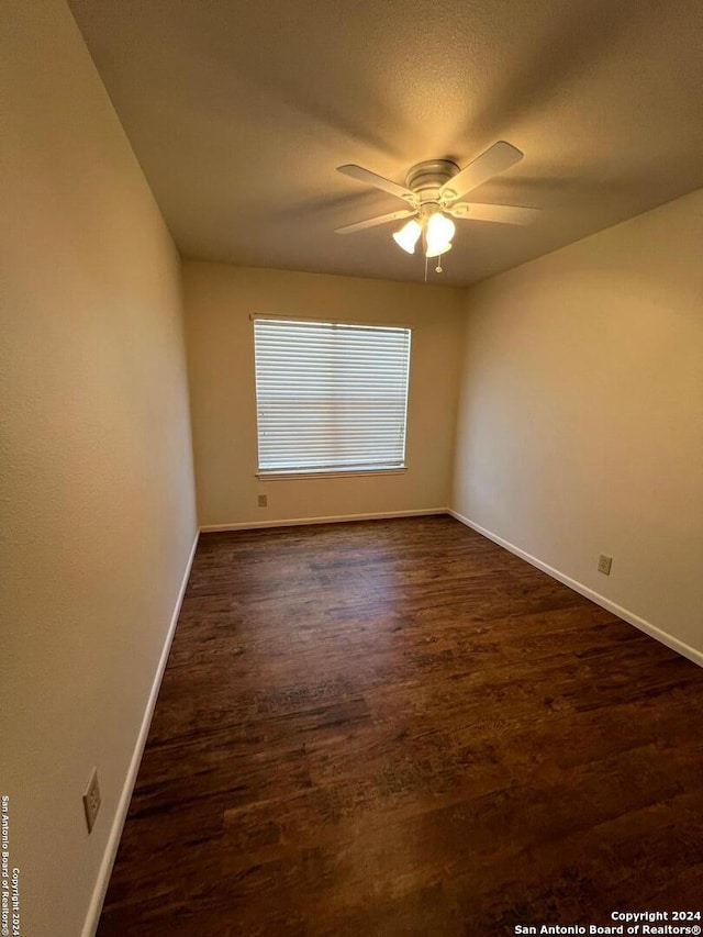 empty room with ceiling fan and dark hardwood / wood-style flooring