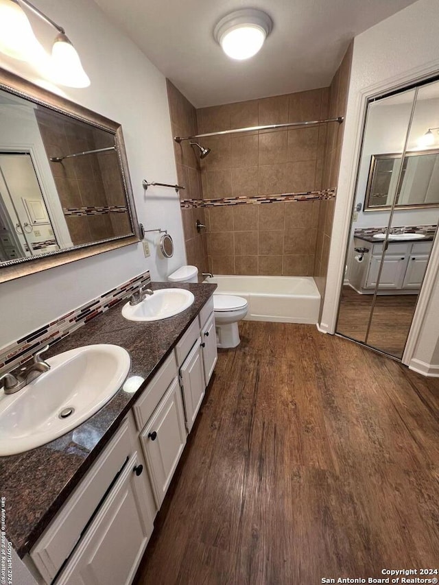 full bathroom with vanity, toilet, wood-type flooring, and tiled shower / bath