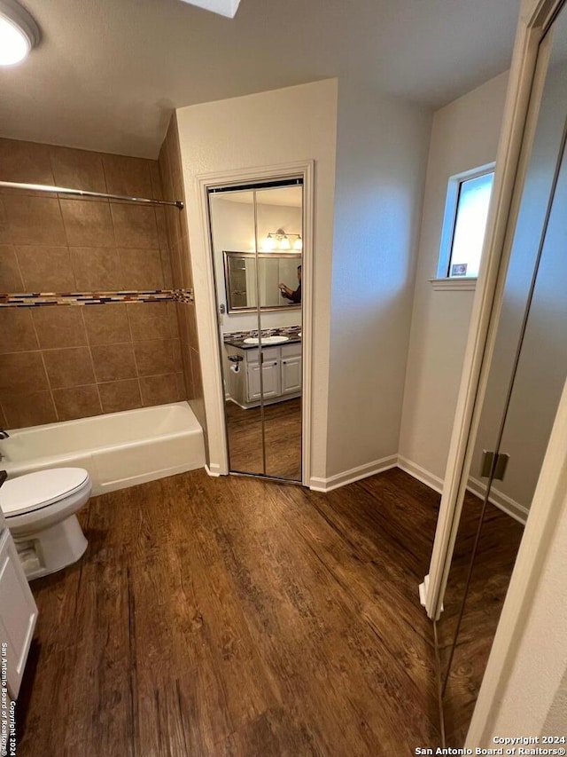 full bathroom with tiled shower / bath, vanity, wood-type flooring, and toilet