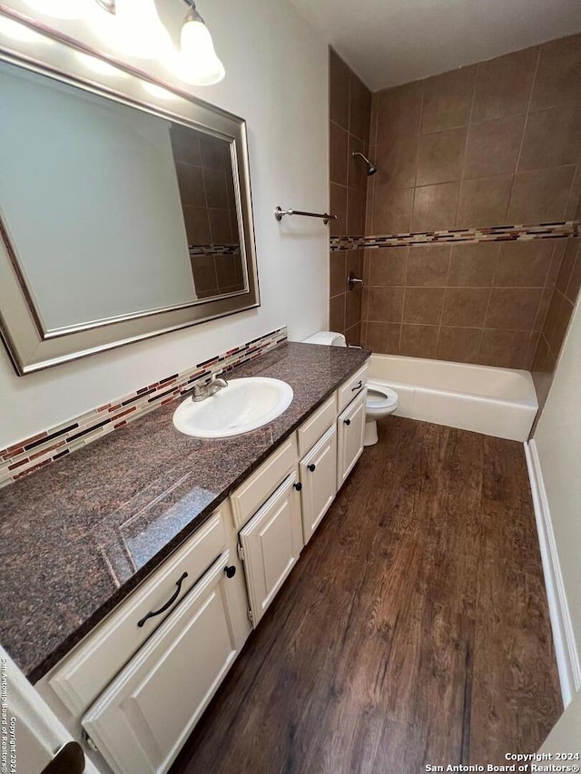 full bathroom featuring toilet, vanity, wood-type flooring, and tiled shower / bath