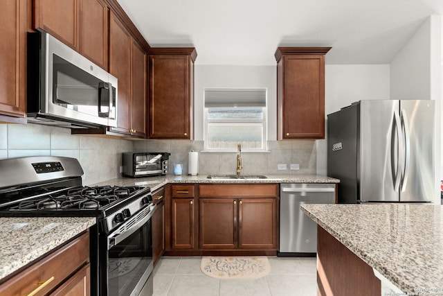 kitchen featuring sink, appliances with stainless steel finishes, tasteful backsplash, light tile patterned flooring, and light stone counters