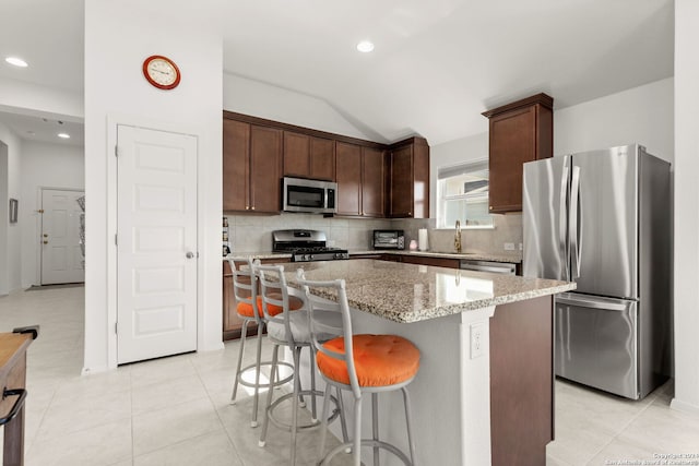 kitchen featuring a center island, stainless steel appliances, light stone counters, and backsplash