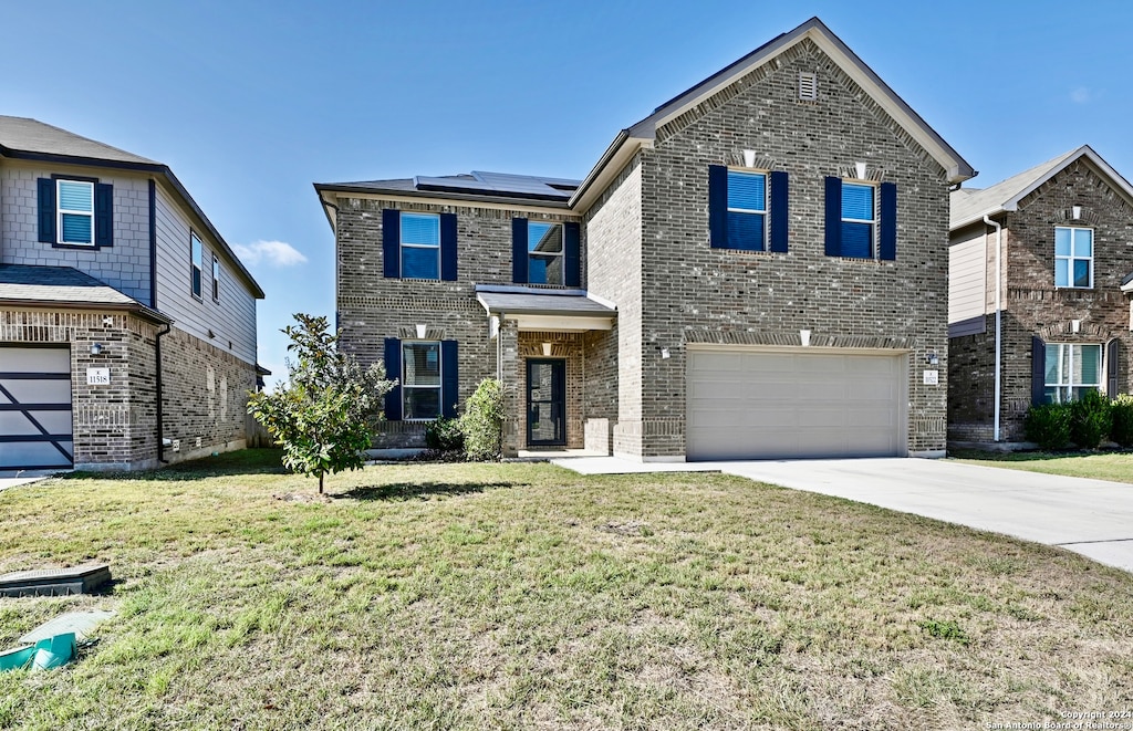 view of front facade with a garage, a front yard, and solar panels