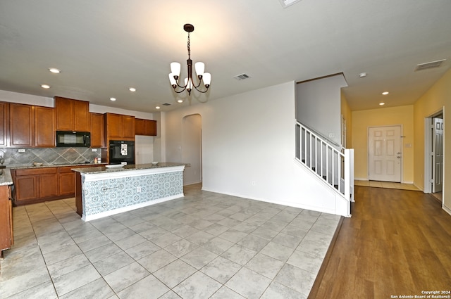 kitchen with a chandelier, pendant lighting, decorative backsplash, a kitchen island, and black appliances