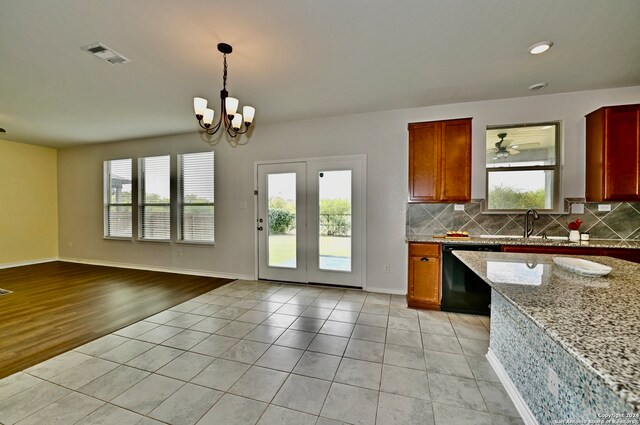 kitchen with dishwasher, light wood-type flooring, light stone countertops, tasteful backsplash, and decorative light fixtures