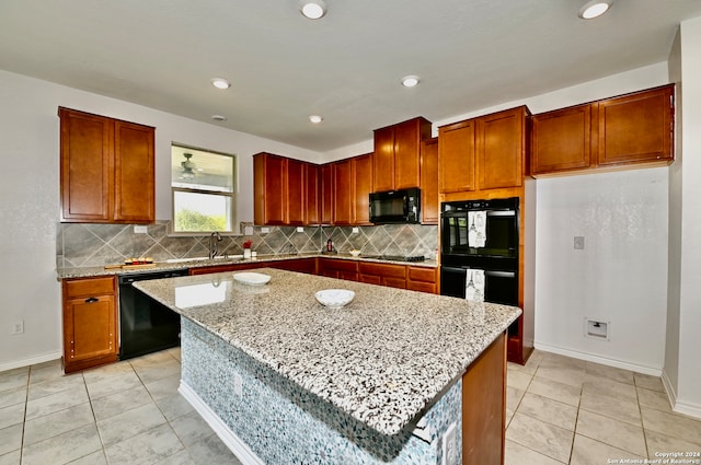 kitchen with black appliances, a kitchen island, light stone countertops, and light tile patterned floors