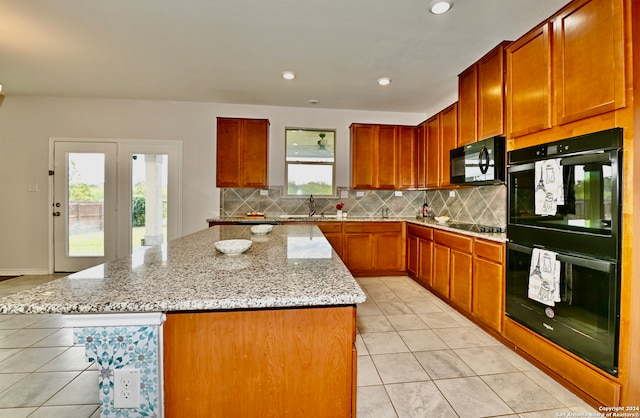 kitchen featuring decorative backsplash, plenty of natural light, a kitchen island, and black appliances