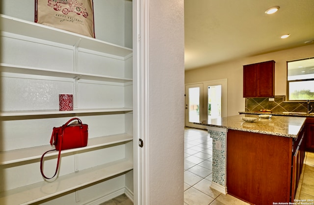 kitchen featuring sink, light stone counters, light tile patterned floors, and backsplash