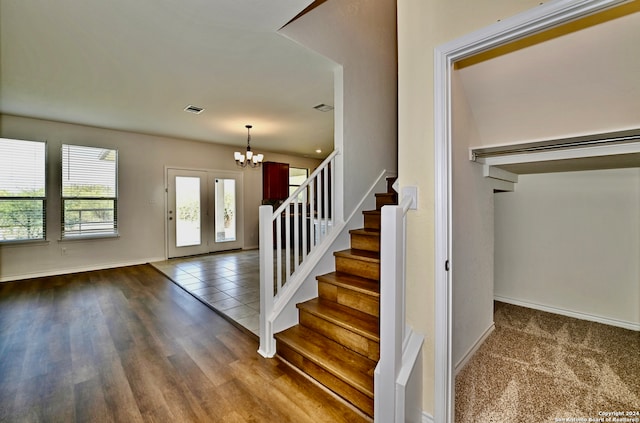 staircase with wood-type flooring and an inviting chandelier