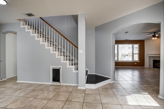 268 Fawn Rdg, Cibolo, TX 78108 - stairs featuring ceiling fan, tile patterned floors, arched walkways, and a fireplace