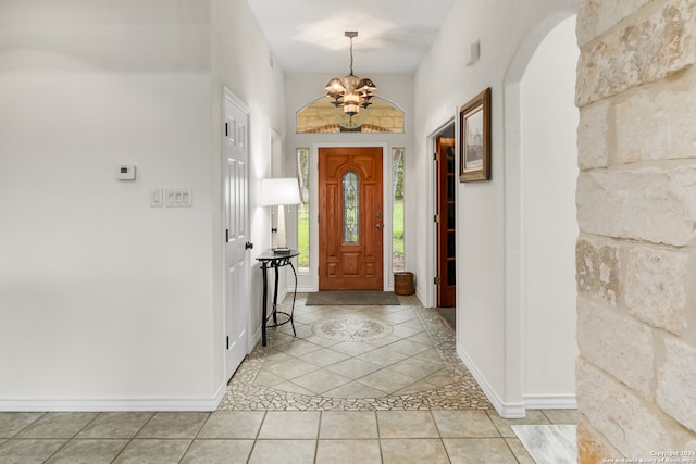 tiled foyer entrance with an inviting chandelier