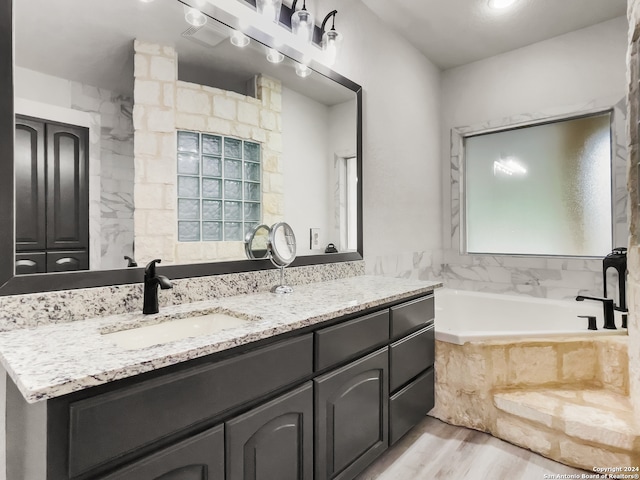 bathroom with vanity, wood-type flooring, and tiled bath