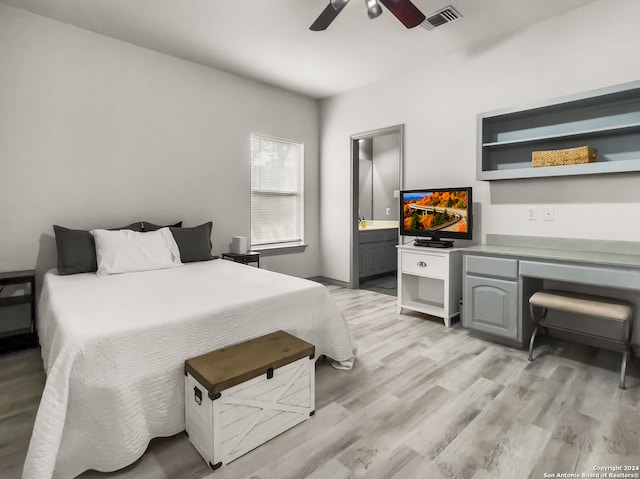 bedroom with built in desk, light hardwood / wood-style floors, ceiling fan, and ensuite bathroom