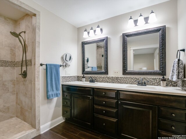 bathroom with a tile shower, decorative backsplash, vanity, and hardwood / wood-style flooring