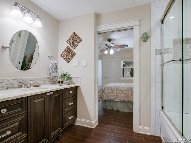 bathroom featuring hardwood / wood-style floors, vanity, ceiling fan, and enclosed tub / shower combo