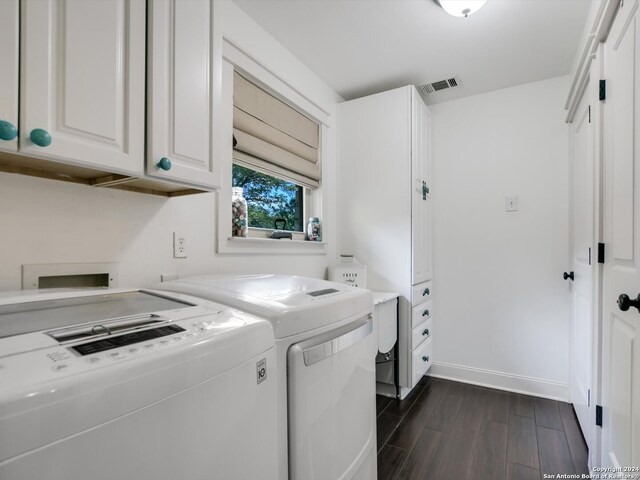 laundry area featuring washing machine and clothes dryer, dark wood-type flooring, and cabinets