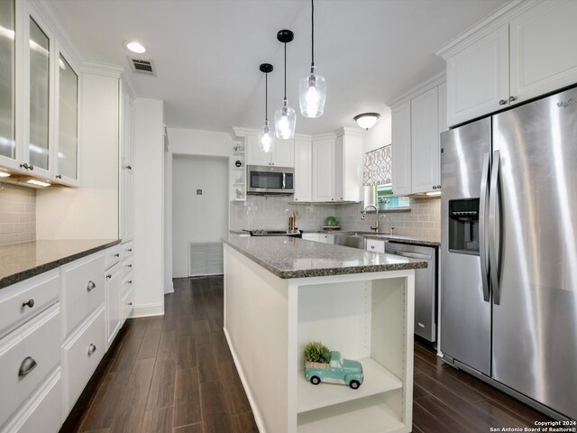 kitchen with white cabinets, appliances with stainless steel finishes, a center island, and dark wood-type flooring