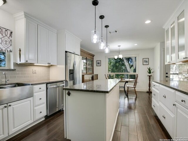 kitchen featuring pendant lighting, a center island, appliances with stainless steel finishes, dark hardwood / wood-style flooring, and white cabinetry