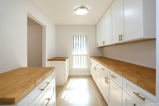 kitchen featuring light wood-type flooring, wood counters, and white cabinetry