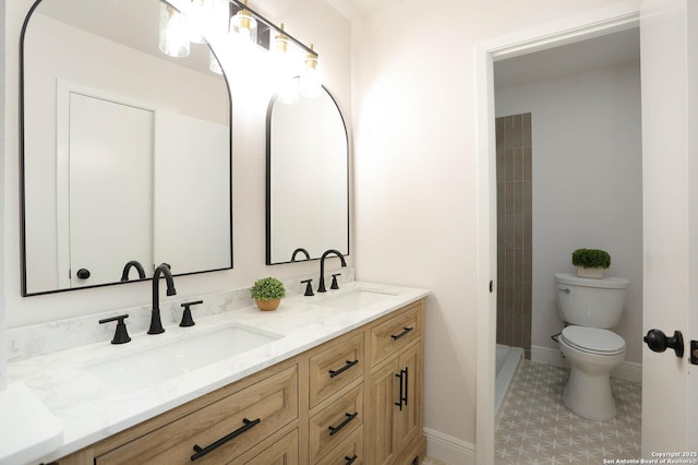 bathroom featuring double vanity, toilet, baseboards, and a sink