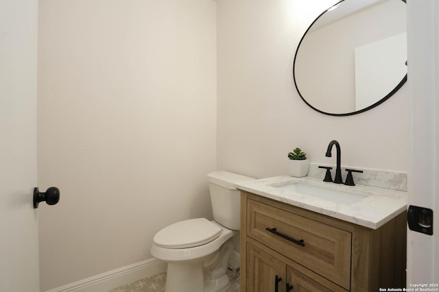 half bathroom featuring toilet, vanity, and baseboards