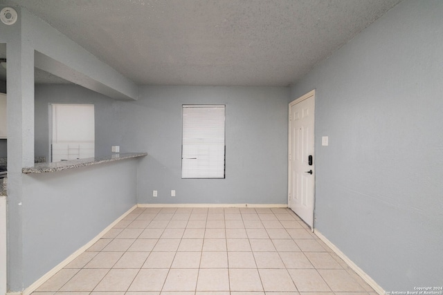 unfurnished room with light tile patterned floors and a textured ceiling