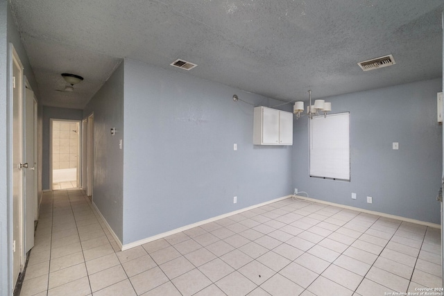 unfurnished room with light tile patterned floors, a chandelier, and a textured ceiling