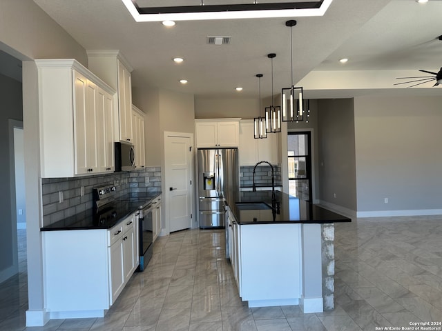 kitchen with stainless steel appliances, a kitchen island with sink, sink, decorative light fixtures, and white cabinets