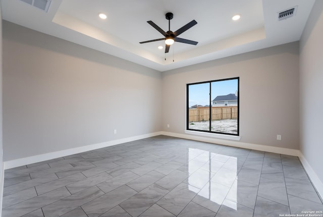 spare room featuring a tray ceiling and ceiling fan