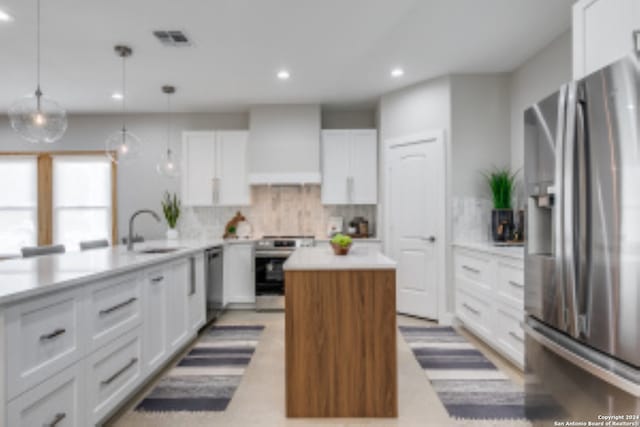 kitchen featuring hanging light fixtures, sink, decorative backsplash, appliances with stainless steel finishes, and white cabinetry