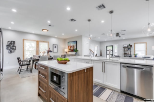 kitchen featuring hanging light fixtures, white cabinetry, stainless steel appliances, and a wealth of natural light