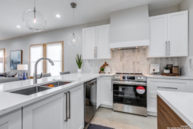 kitchen with premium range hood, white cabinetry, decorative light fixtures, and appliances with stainless steel finishes