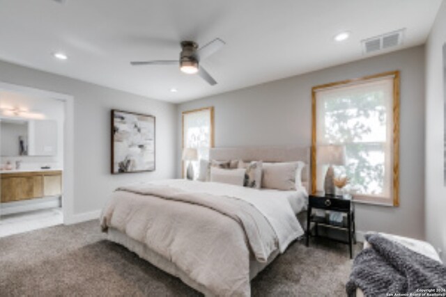 carpeted bedroom featuring ceiling fan, ensuite bath, and multiple windows