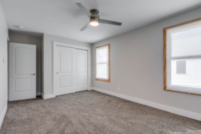 unfurnished bedroom with light carpet, a closet, and ceiling fan