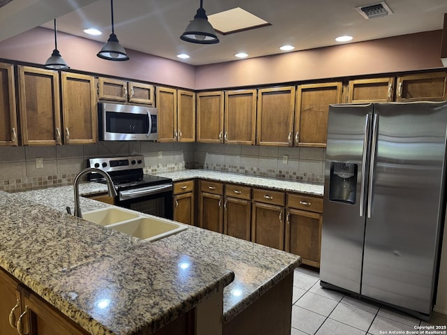 kitchen featuring stainless steel appliances, brown cabinets, decorative light fixtures, and visible vents