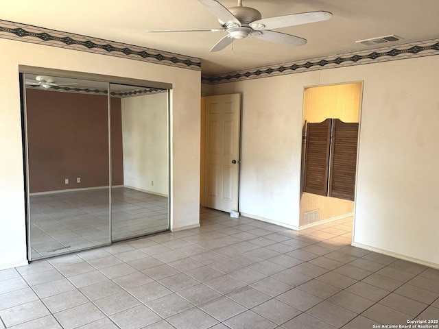 unfurnished bedroom with a closet, visible vents, light tile patterned flooring, ceiling fan, and baseboards