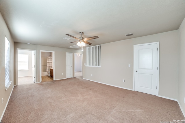 unfurnished bedroom featuring ensuite bathroom, ceiling fan, and light colored carpet