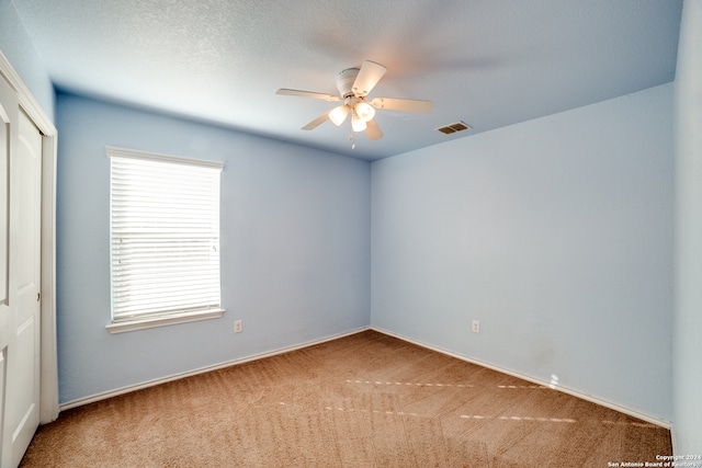 carpeted spare room with ceiling fan and a textured ceiling