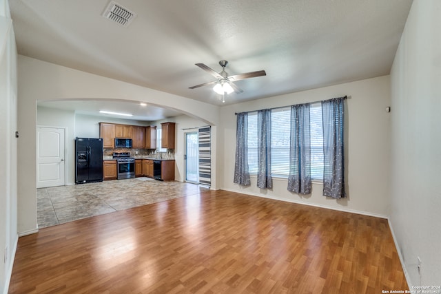 unfurnished living room featuring ceiling fan, sink, light hardwood / wood-style floors, and a textured ceiling