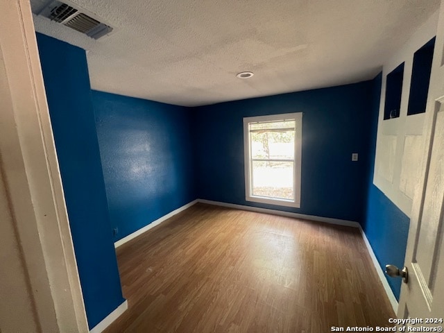 empty room with dark hardwood / wood-style flooring and a textured ceiling