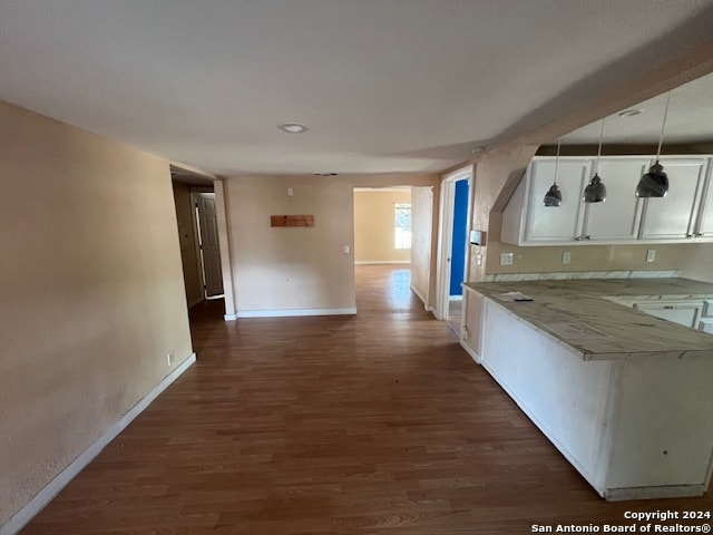 kitchen featuring decorative light fixtures, light stone counters, white cabinetry, and dark wood-type flooring