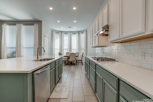 kitchen with decorative backsplash, stainless steel appliances, a kitchen island with sink, sink, and light tile patterned floors