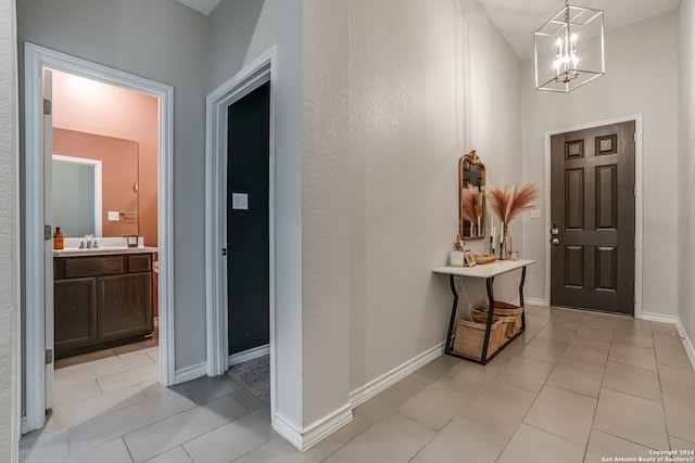 tiled foyer featuring sink and a notable chandelier