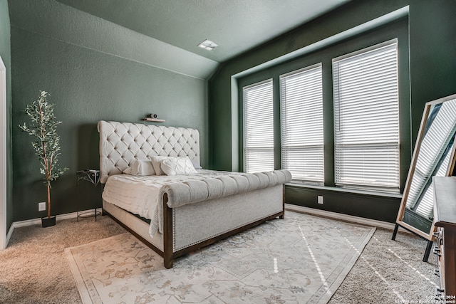 carpeted bedroom featuring a textured ceiling and vaulted ceiling