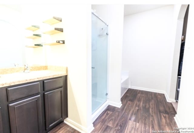 bathroom with hardwood / wood-style flooring, vanity, and plus walk in shower