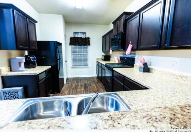 kitchen featuring black appliances, dark hardwood / wood-style flooring, and light stone countertops