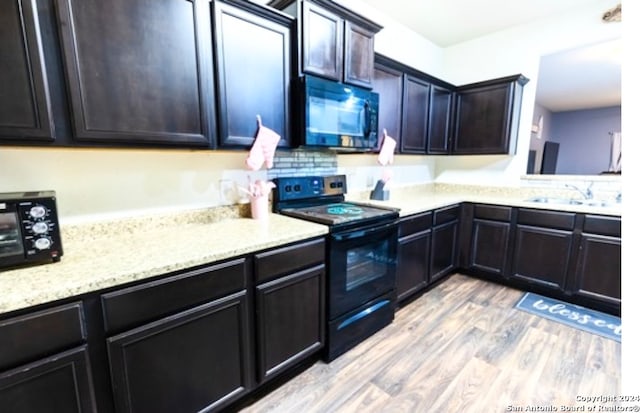 kitchen with black appliances, light hardwood / wood-style floors, and sink